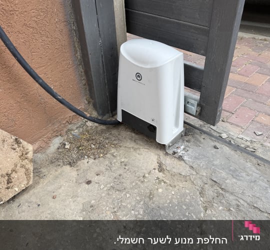 מנוע חשמלי לשער חניה ליד קיר בטון